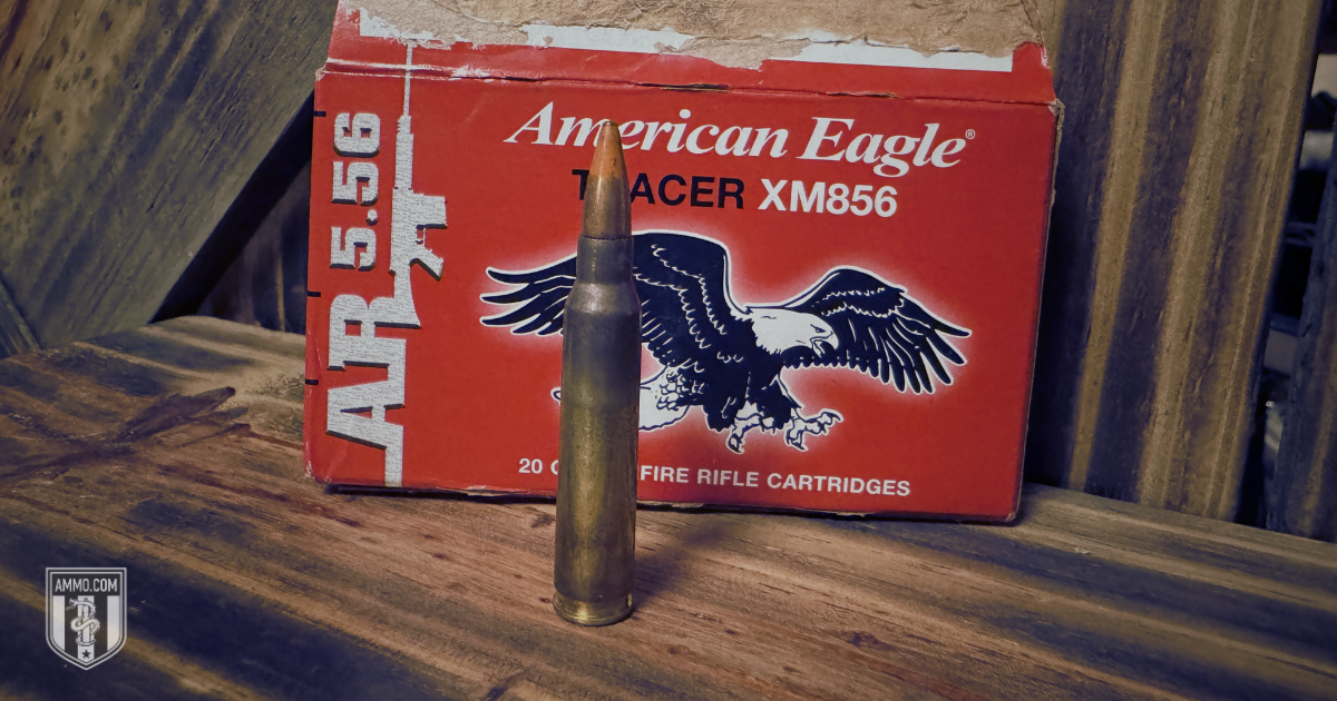 Federal American Eagle AR 5.56 XM856 tracer cartridge leaning against its ammo box