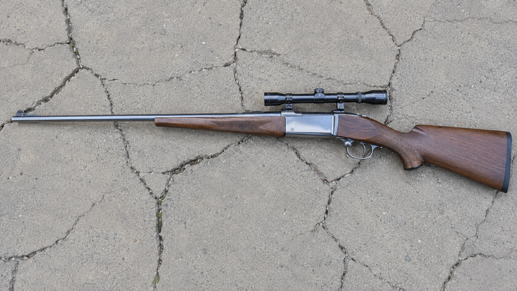 Scoped Savage Model 99 lever-action rifle laid on cracked concrete